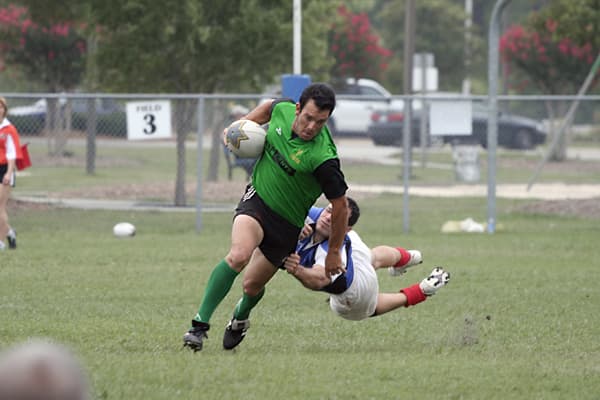 A rugby player running through a tackle